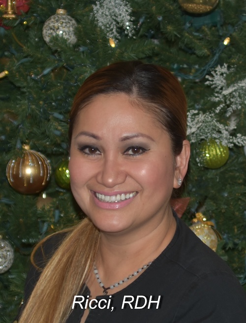 A smiling woman posing in front of a Christmas tree, with the text  Ricci, DH  visible.