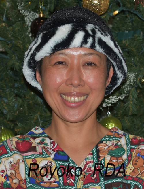 Woman wearing a zebra print hat and a festive outfit, posing for a Christmas photo with a tree in the background.
