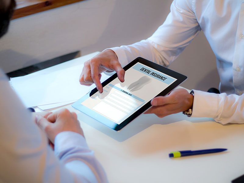 Two individuals interacting with a tablet displaying a document, likely in a professional setting.