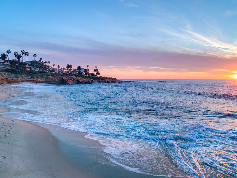 The image depicts a serene beach scene at sunset, with the horizon line visible and a picturesque view of the ocean meeting the sky.