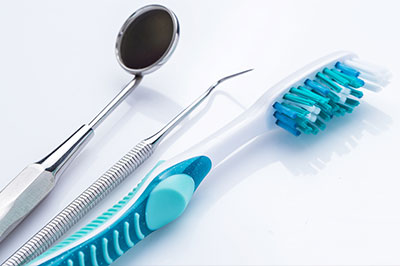 A dental tool set with a toothbrush and a pair of scissors, displayed against a white background.