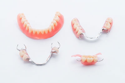 The image shows a set of dentures with upper and lower bridges, displayed against a white background.