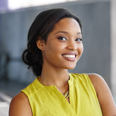 The image features a woman with a radiant smile, posing confidently in front of a building.