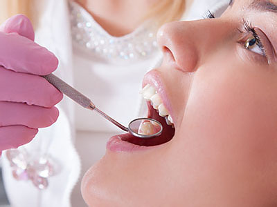The image shows a dental professional performing an oral procedure on a patient, with the focus on the dental tools and the close-up of the patient s mouth.