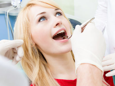 A woman receiving dental care, with a dentist performing the procedure and assistants observing.