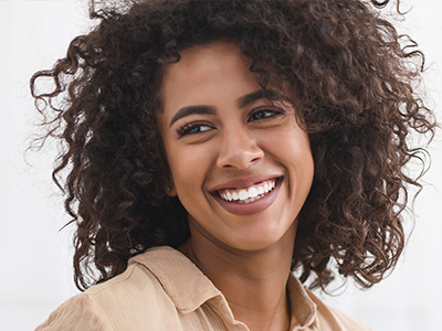 The image shows a woman with curly hair smiling at the camera.